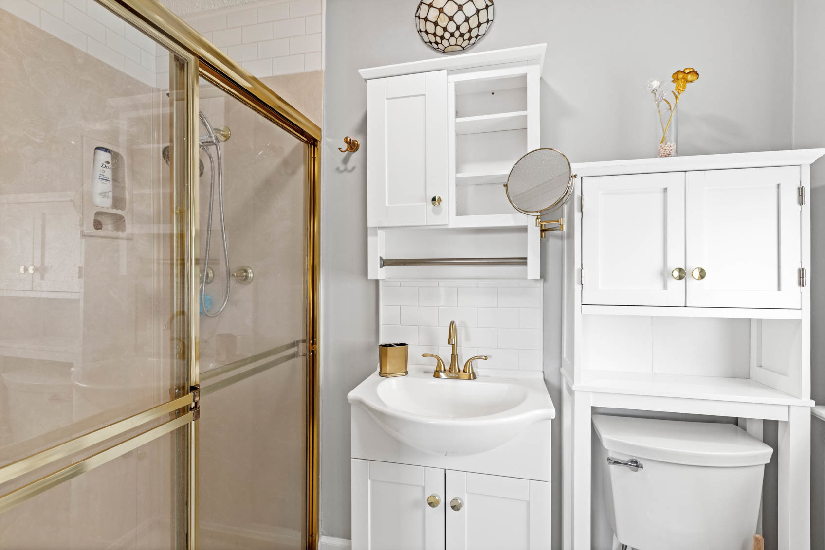 small bathroom with white above toilet cabinet and shower
